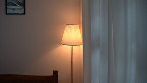 A room with a standing floor lamp, a bed, and a curtain.