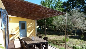 Een terras met een tafel, stoelen, een blauwe deur en een pergola.