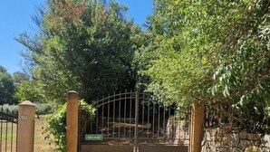 Een hekpoort met een metalen poort, een stenen muur en een bord met de tekst 'Gite rural'.