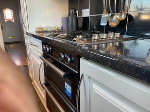 A kitchen with a black countertop, stainless steel appliances, and a white cabinet. - The Gold- Home Away From Home (Manchester)
