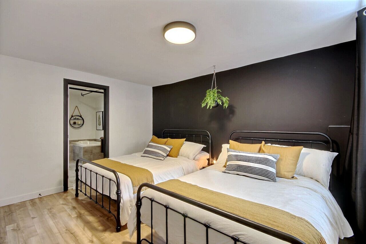 A bedroom with two beds, a hanging plant, and a mirror.