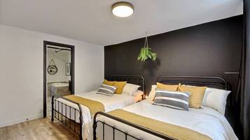 A bedroom with two beds, a hanging plant, and a mirror.
