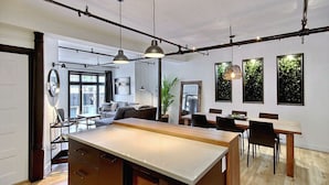 Una cucina moderna con isola centrale, illuminazione a sospensione e zona pranzo con tavolo e sedie in legno.