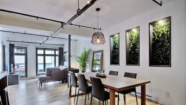 Zona pranzo moderna con tavolo e sedie in legno, lampadario a sospensione e quadri appesi alle pareti.