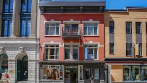 Un edificio a più piani con facciata in mattoni rossi, ampie finestre e un balcone.