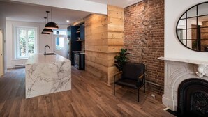 Una cucina moderna con isola in marmo, rivestimenti in legno e una parete a mattoni.
