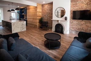A modern living space with a kitchen, a fireplace, and a TV mounted on a brick wall.
