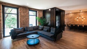 A modern living room with a sectional sofa, a round coffee table, and a dining area with a brick wall and hanging lights. - Château Deluxe / / Vieux-Québec, Énorme Maison (Québec)