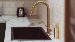 A kitchen with white subway tiles, a gold faucet, and a black sink. - Château Deluxe / / Vieux-Québec, Énorme Maison (Québec)