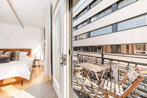 Una camera da letto con un letto, un comodino e vista su un balcone con tavolo e sedie.