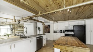 Cozinha moderna com armários brancos, bancada de madeira e geladeira preta.
