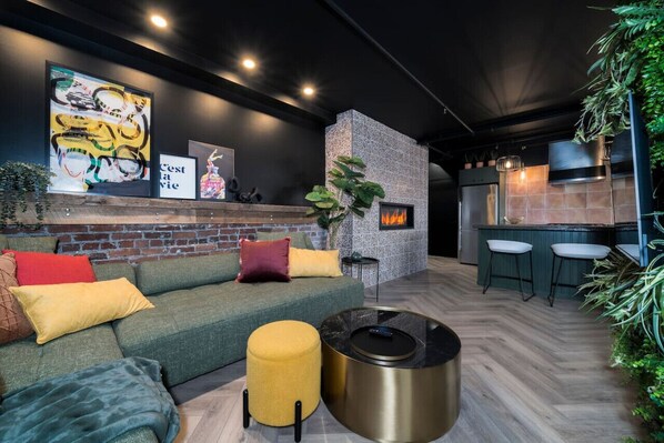Ein modernes Wohnzimmer mit Kamin, einer Couch, einem Couchtisch und einer Küchenzeile mit Barhocker.