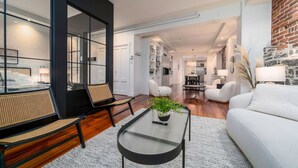 Ein modernes Wohnzimmer mit einem Glastisch, weißen Sofas und einem großen Fenster.