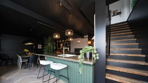 Eine moderne Küche mit Barbereich, einer Holztreppe und Pendelleuchten.