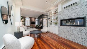 Ein modernes Wohnzimmer mit Kamin, weißen Möbeln und einer Wand mit Farbflecken.