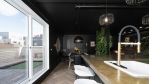 Eine moderne Küche mit großem Fenster, weißen Barhocker und integriertem Spülbecken.
