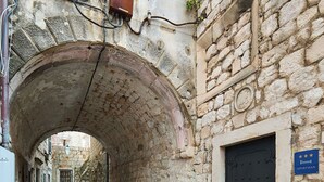 A narrow stone-paved alleyway with a black door and a sign indicating it is an apartment. - Hedera Estate, Villa Hedera XVII (Dubrovnik)