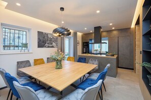 Un'area pranzo moderna con tavolo in legno, sedie imbottite e lampada a sospensione.