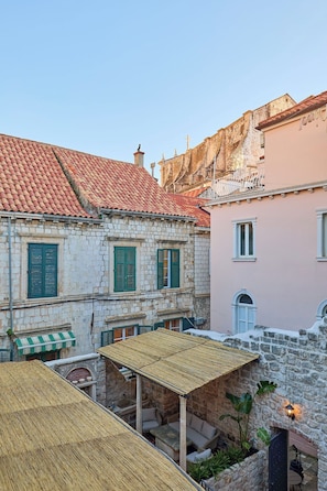 Un cortile con edifici in pietra, un'area salotto coperta e un piccolo giardino.