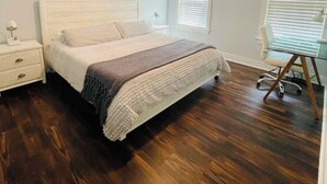 A bedroom with a bed, a nightstand, a desk, and a ceiling fan.
