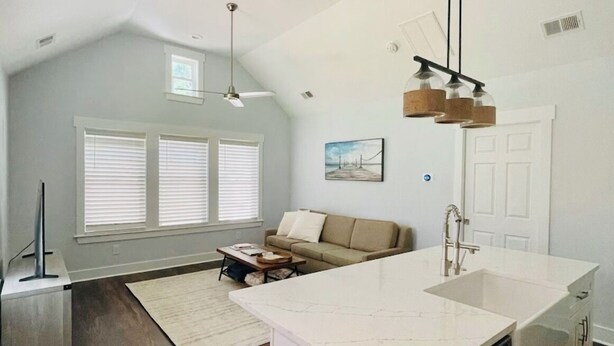Una cocina moderna con una isla grande, un comedor con sofá y un ventilador de techo.