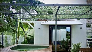 A modern outdoor structure with a pool, surrounded by lush greenery and a covered area with string lights. - Jala Jala Casita Blanca Tiny House and Farm Stay with Mountain View and Pool (Jala Jala)