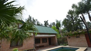 Una casa in mattoni con tetto verde, piscina e vegetazione circostante.