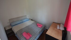 Un letto singolo con biancheria a motivi, un comodino e un tavolino con asciugamani.