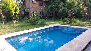 A rectangular swimming pool with blue tiles and a tiled border.