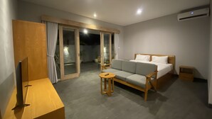 Et moderne hotelværelse med sofa, lille bord, fjernsyn og seng.