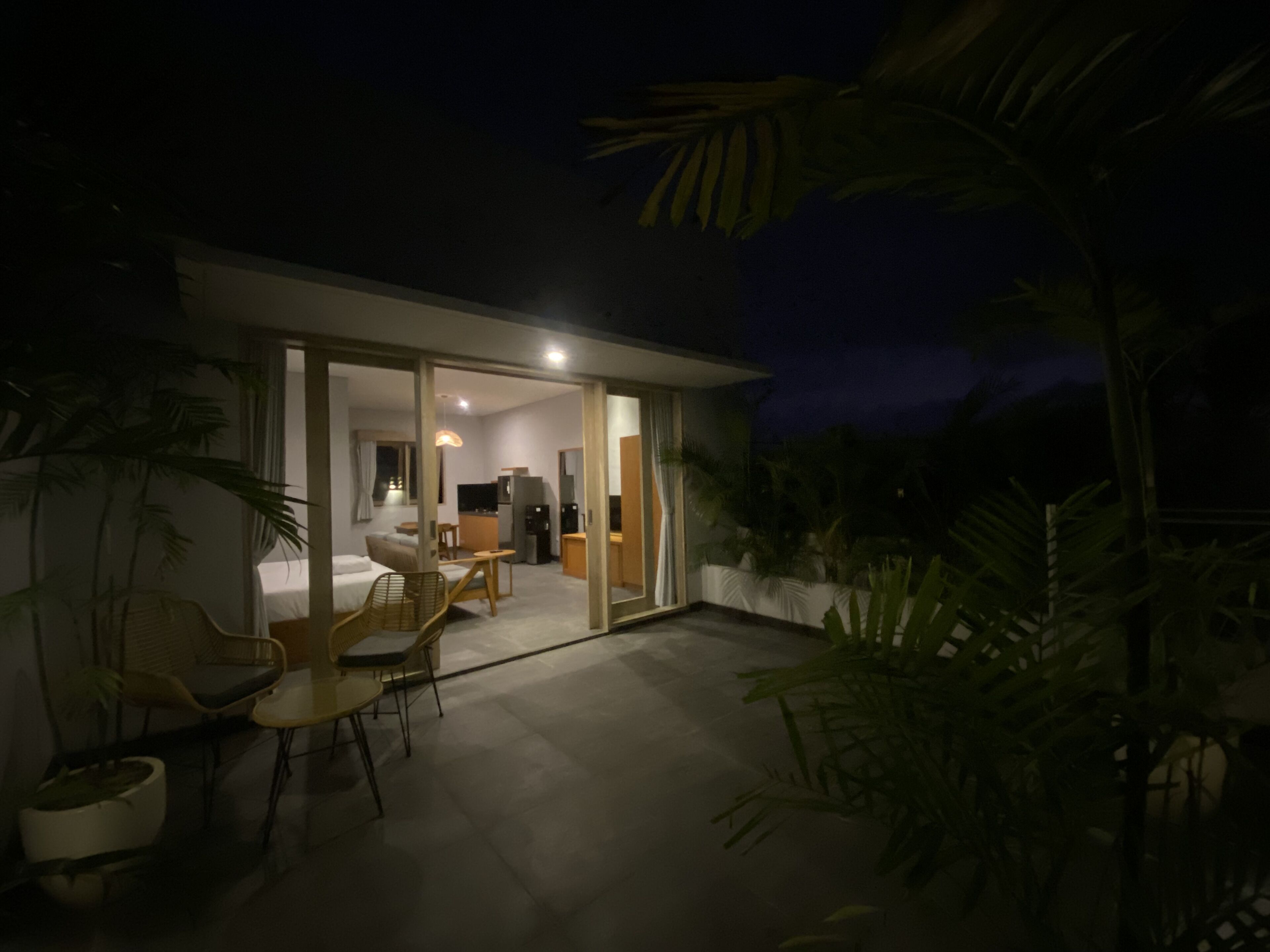 A modern house with a glass door leading to a living area with a sofa, chairs, and a dining table.