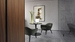 A modern room with a round table, two chairs, a vase with flowers, and a framed abstract painting on the wall. - The Bank Hotel - Etruria Collection (Perugia)