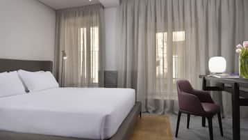 Ein Hotelzimmer mit einem großen Bett, einem Schreibtisch mit Stuhl und einer Lampe.