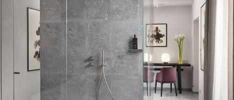 A modern bathroom with a glass shower enclosure, marble walls, and a minimalist design.