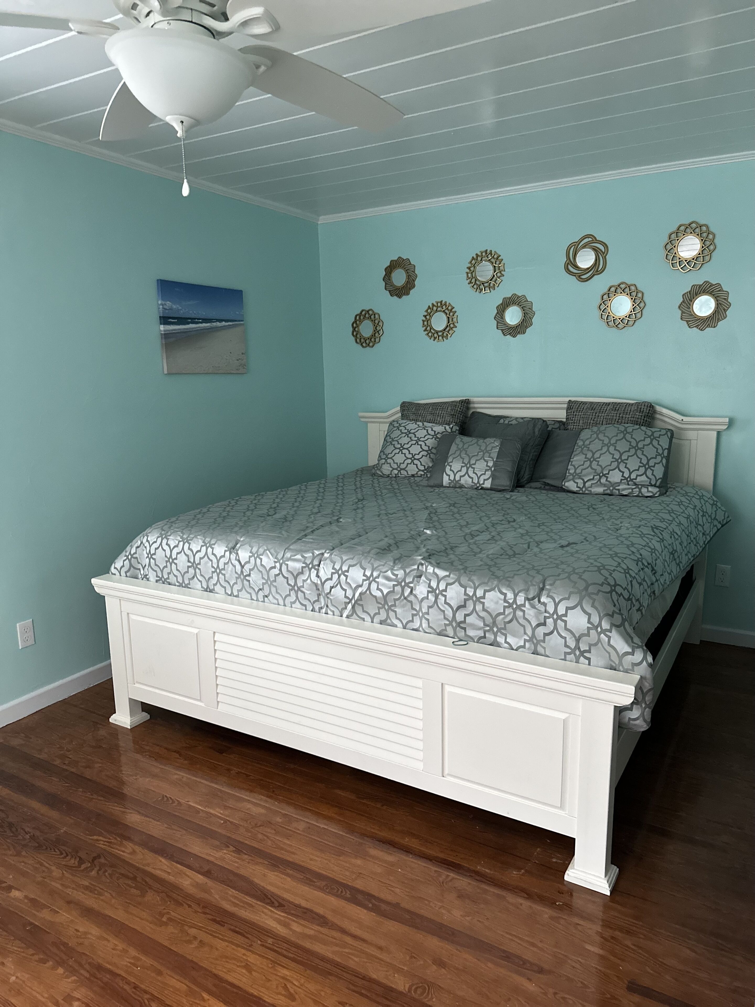 Un dormitorio con cama, ventilador de techo y espejos decorativos en la pared.