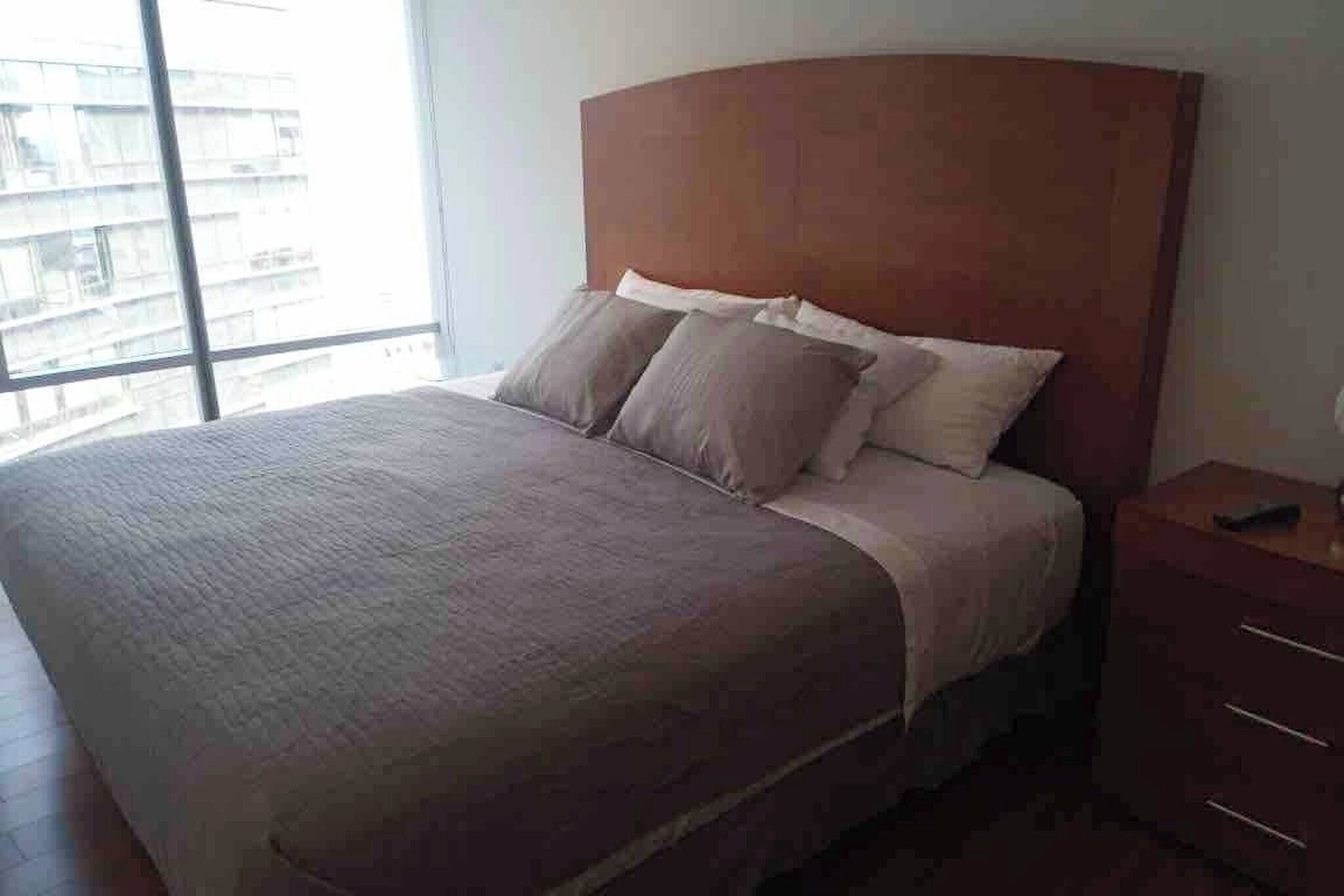 A bedroom with a large bed, a wooden headboard, and a nightstand with drawers.