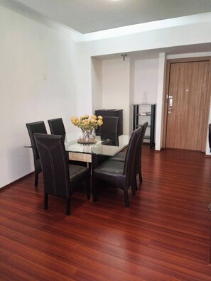 A dining area with a glass table, black chairs, and a vase of yellow flowers.