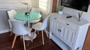A small, modern room with a round table, white chairs, a white cabinet, and a TV mounted on the wall. - Cozy place in Calusa Key Largo (Key Largo)