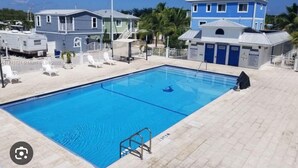 A swimming pool with a metal ladder, surrounded by a white fence and a few lounge chairs. - Cozy place in Calusa Key Largo (Key Largo)