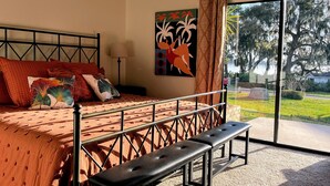 A bedroom with a bed, bench, and a view of the outdoors.