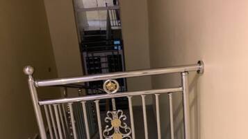 A staircase with a metal railing, a tiled floor, and a beige wall.