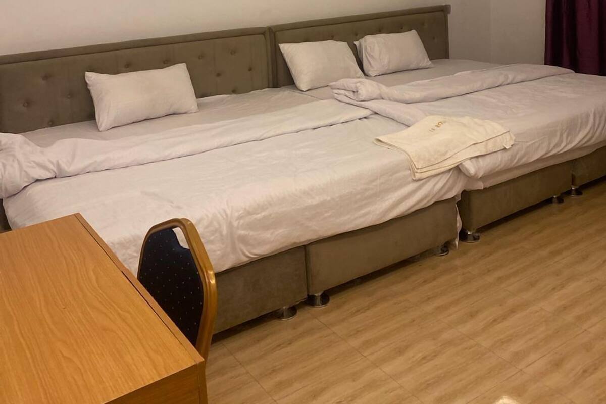 A hotel room with a double bed, a wooden desk, and a chair.