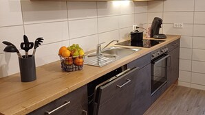 A modern kitchen with grey cabinets, a wooden countertop, and a built-in dishwasher. - Gemütliche Ferienwohnung mit Kamin (Emmingen-Liptingen)