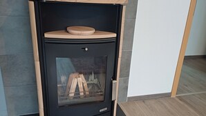 A modern wood-burning stove with a glass door, a wooden top, and a yellow plant on top. - Gemütliche Ferienwohnung mit Kamin (Emmingen-Liptingen)