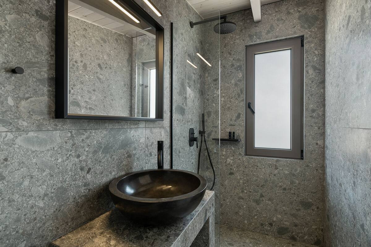 Un baño moderno con un lavamanos grande y redondo, un espejo y una zona de ducha.