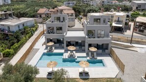 A modern hotel with a rooftop pool, multiple balconies, and a view of the surrounding landscape. - Casa Nostos (Chania)