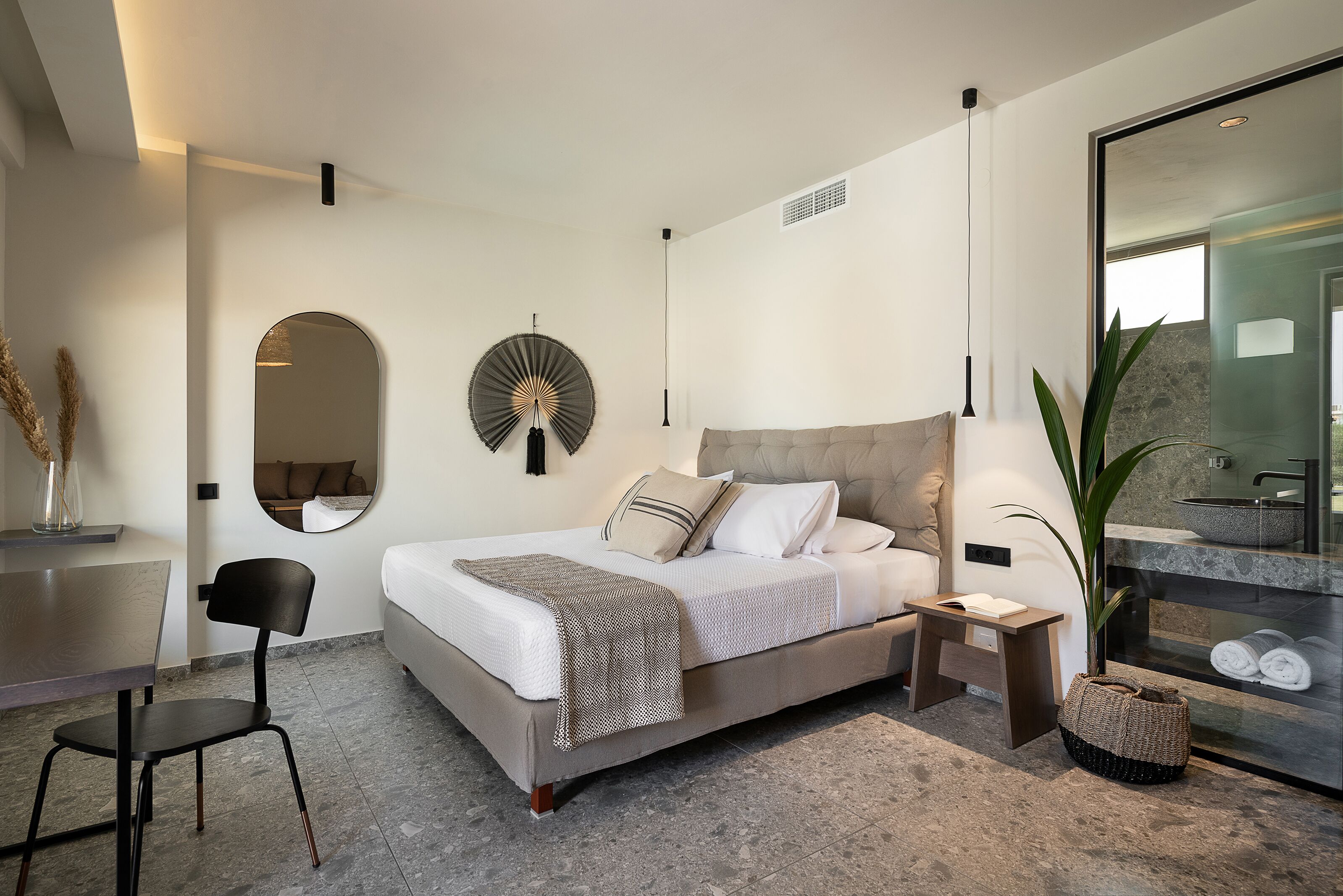 A modern bedroom with a bed, bedside table, chair, and a large mirror.