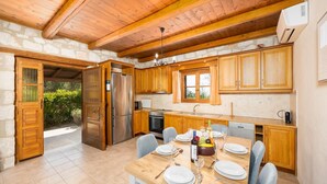 Une cuisine avec des meubles de rangement en bois, un réfrigérateur en acier inoxydable et une table à manger pour quatre personnes.