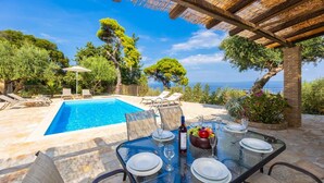 Un espace repas aménagé au bord de la piscine, avec une table pour deux, offrant une vue sur la piscine et un paysage pittoresque.