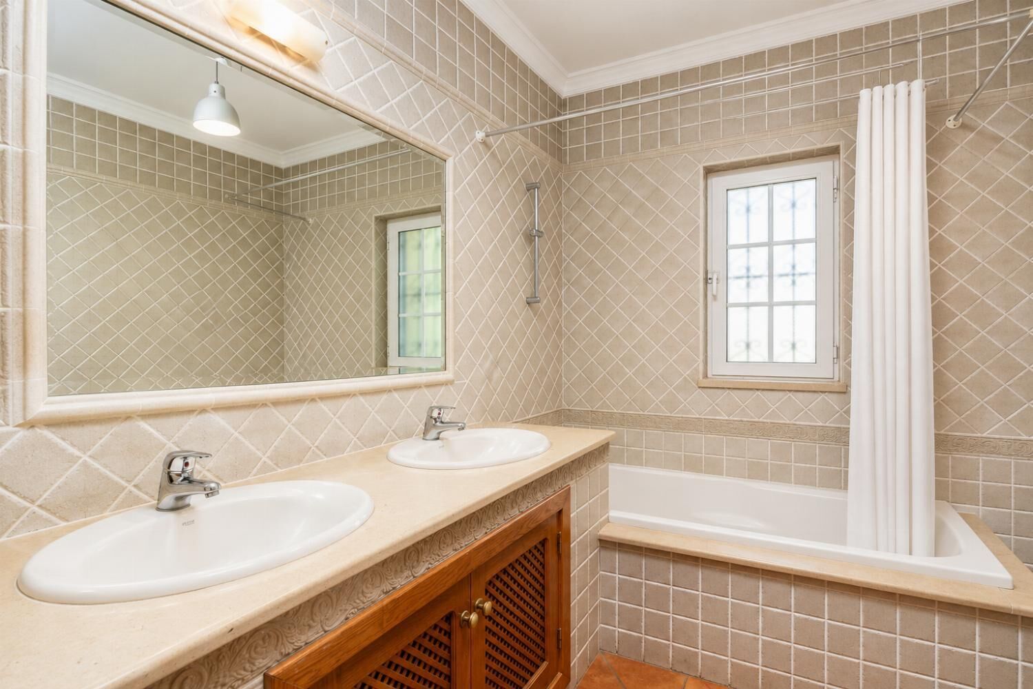 Un baño con dos lavamanos, un espejo, una ducha y una ventana.